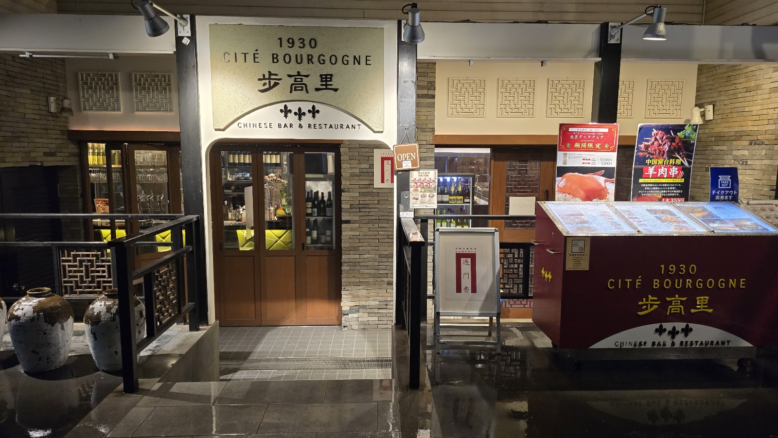夜の店先。金文字の看板、木の扉、格子の欄干、白い甕。